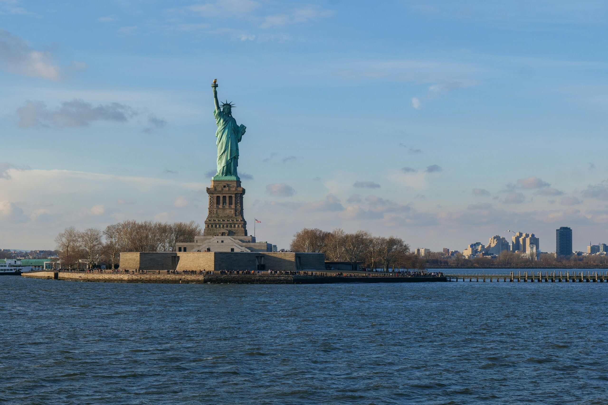 Iconic view of the Statue of Liberty against New York City's skyline on a clear day.