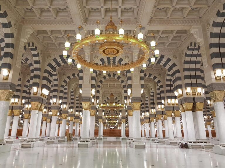 Umrah Stunning architecture of the Prophet's Mosque interior in Medina, Saudi Arabia with grand chandeliers and columns.